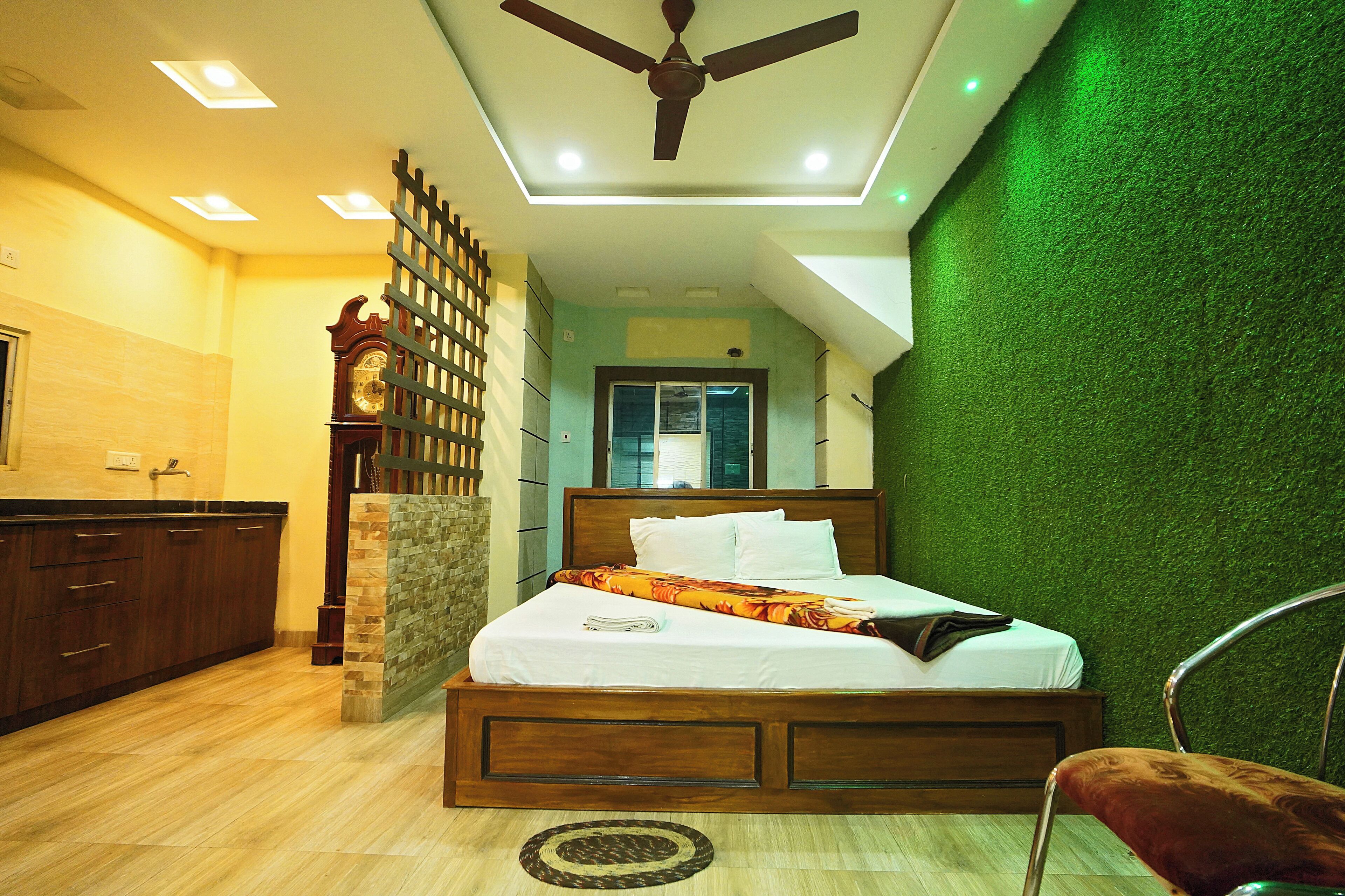 A bedroom with a wooden bed, a ceiling fan, a green wall, and a wooden dresser.