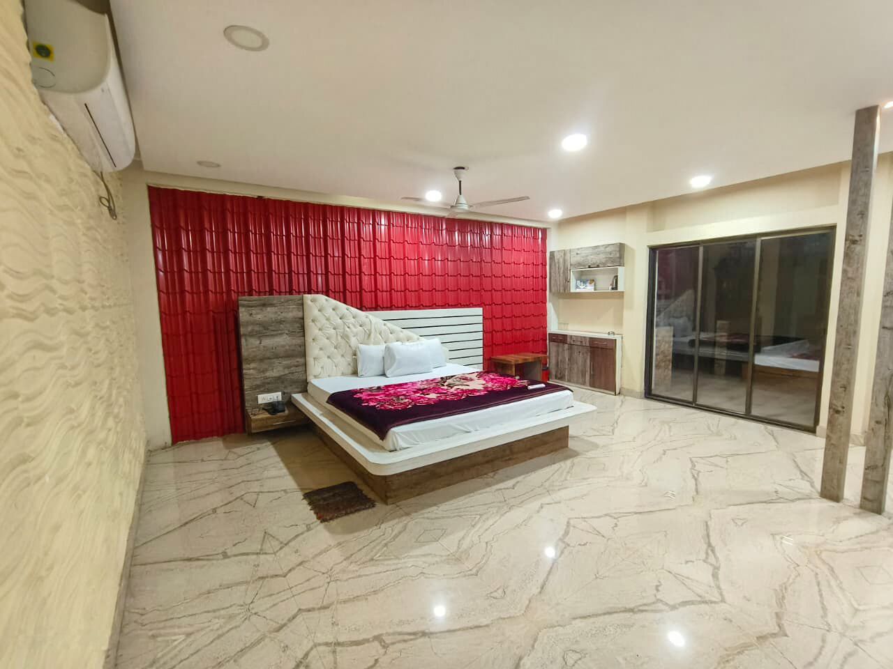 Un dormitorio con una cama, una cortina roja, un ventilador de techo y un ventanal corredero.