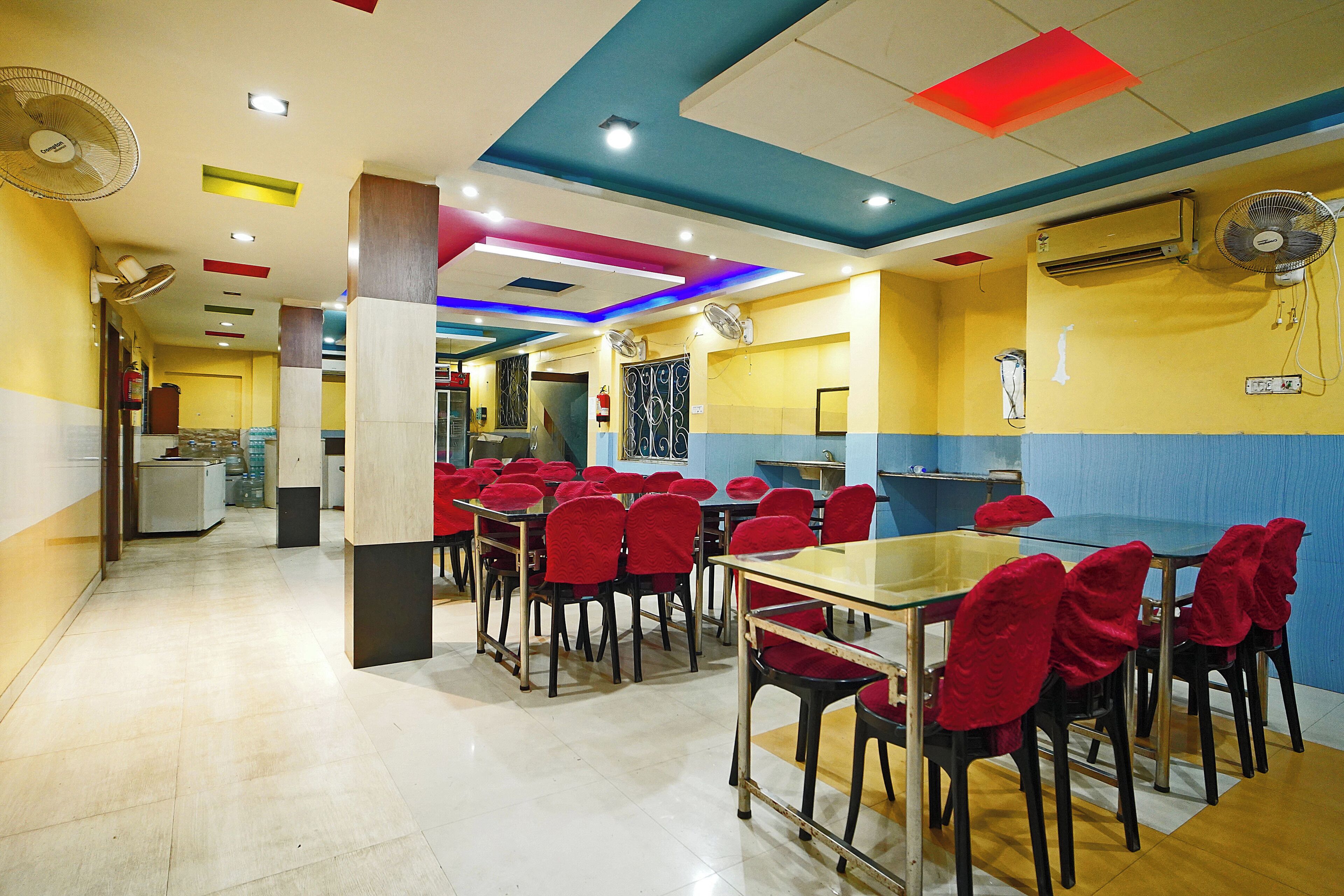 A dining area with tables and chairs, ceiling fans, and recessed lighting.