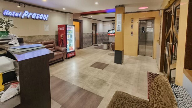 A hotel lobby with a reception desk, a Coca-Cola refrigerator, a couch, and a Coca-Cola advertisement.