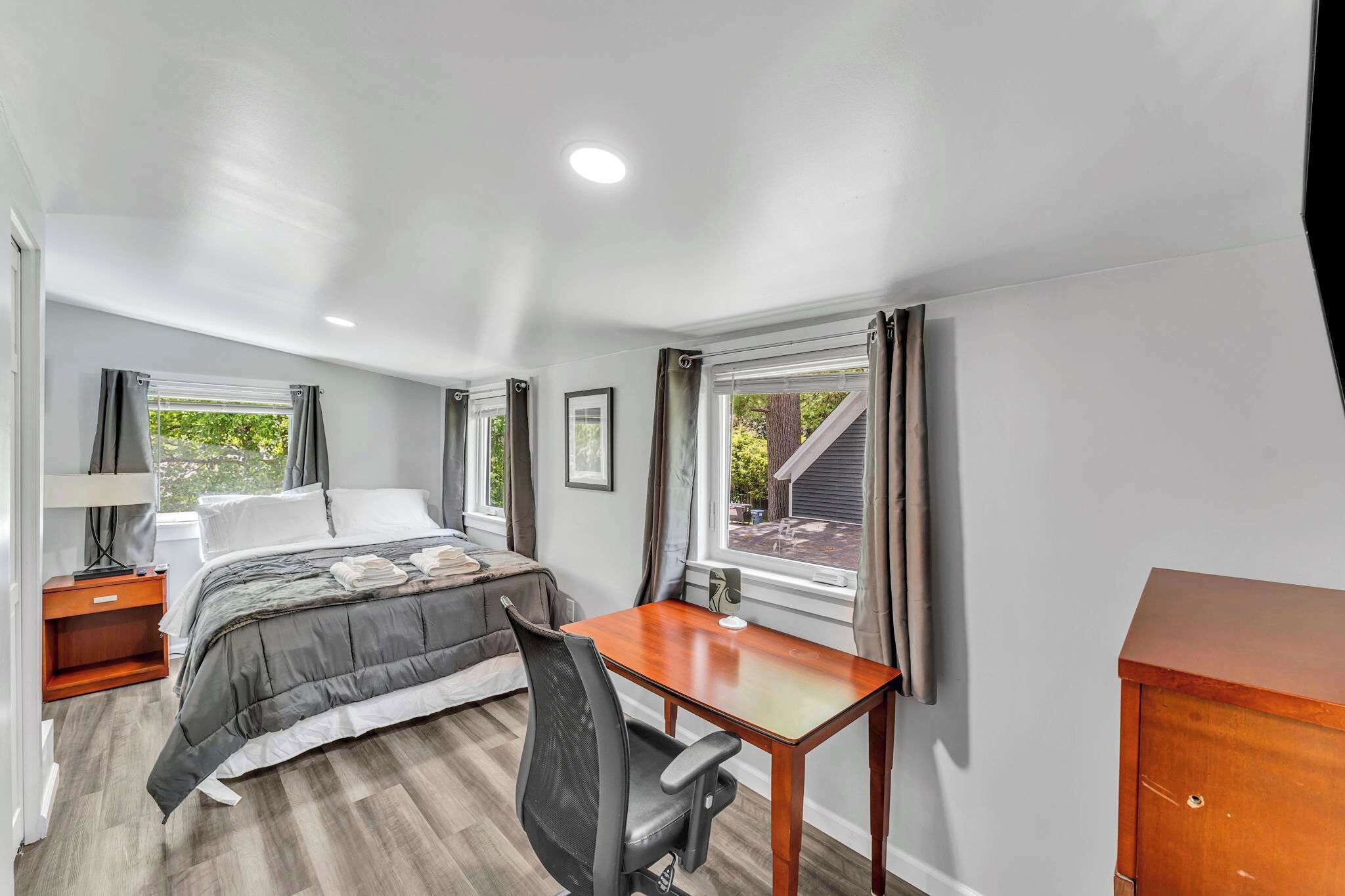 A compact bedroom with a bed, a desk, and a chair.