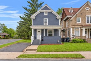 A two-story residential house with a front porch, a garage, and a well-maintained lawn. - Pitcher's Paradise Apt 3 - All Star Baseball Rentals (Oneonta)