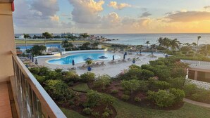 A pool area with lounge chairs and umbrellas, surrounded by landscaped gardens and a view of the sea. - Paradise Perch - Royal Retreats at Maho Beach (Lowlands)
