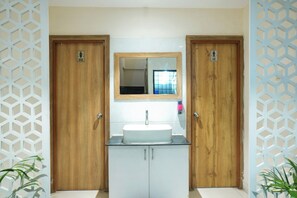 Un bagno con due porte in legno, un lavandino bianco e uno specchio sopra.