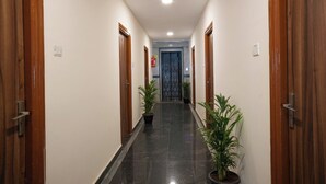 Un pasillo con puertas de madera, plantas en macetas y suelo de baldosas.