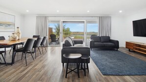 A modern living room with a dining area, a sofa, and a TV. - The Pit Stop Tailem Bend (Tailem Bend)
