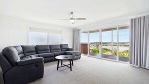 A modern living room with a sectional sofa, a small round table, and a ceiling fan. - The Pit Stop Tailem Bend (Tailem Bend)