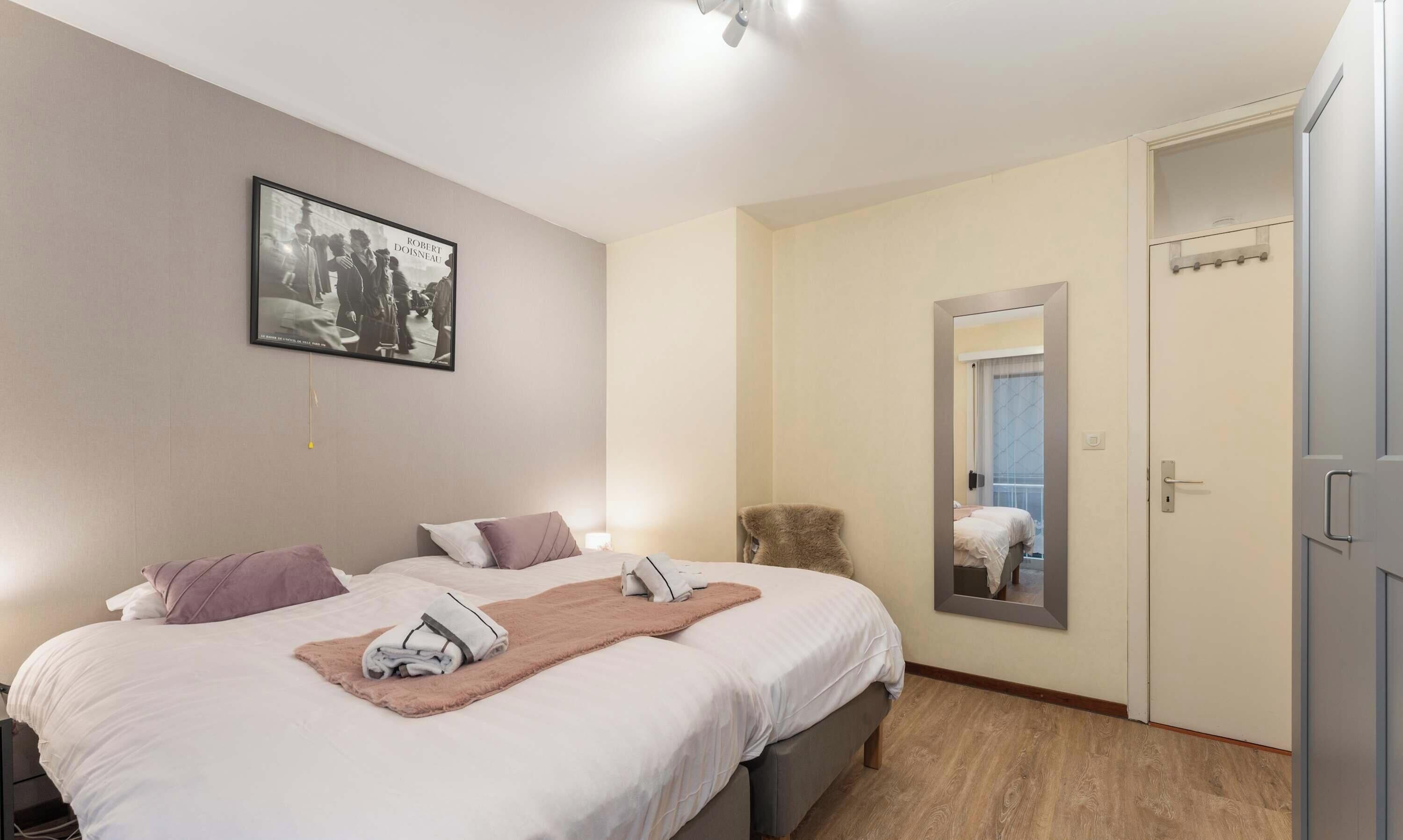 Habitación de hotel con cama, espejo, armario y una foto en el marco en la pared.