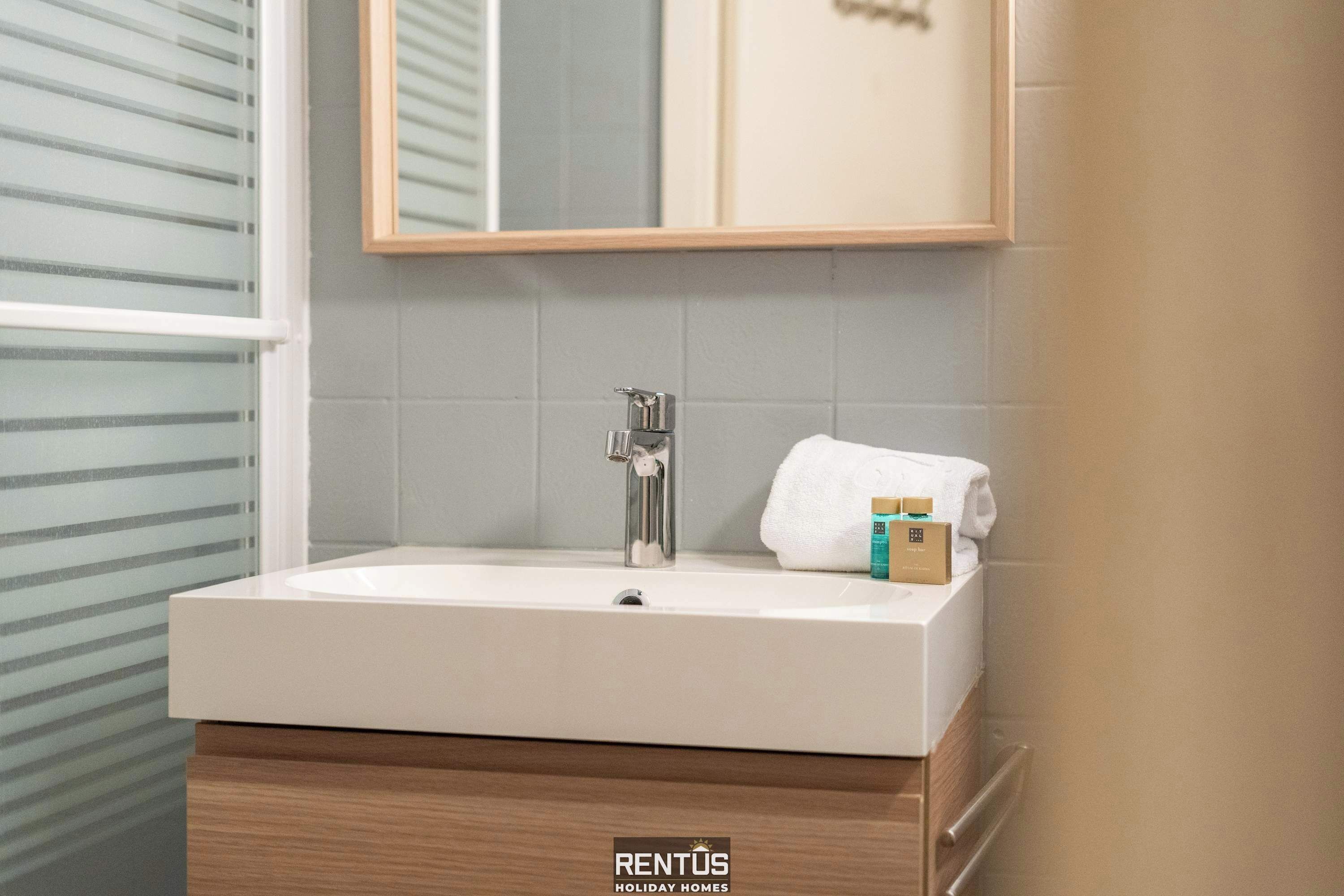 Ein Badezimmer mit einem weißen Waschbecken, einem Spiegel und einem Handtuch.