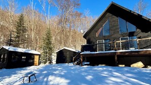 Eine Hütte mit einer gro ßen Terrasse, umgeben von schneebedecktem Boden und Bäumen.