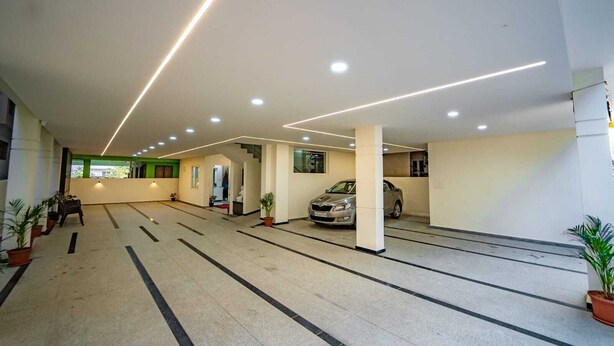 Un ampio parcheggio interno con diverse auto, piante in vaso e un moderno design del soffitto.