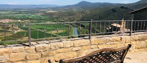 Un muro de piedra con un banco que da a un valle con campos y un río.