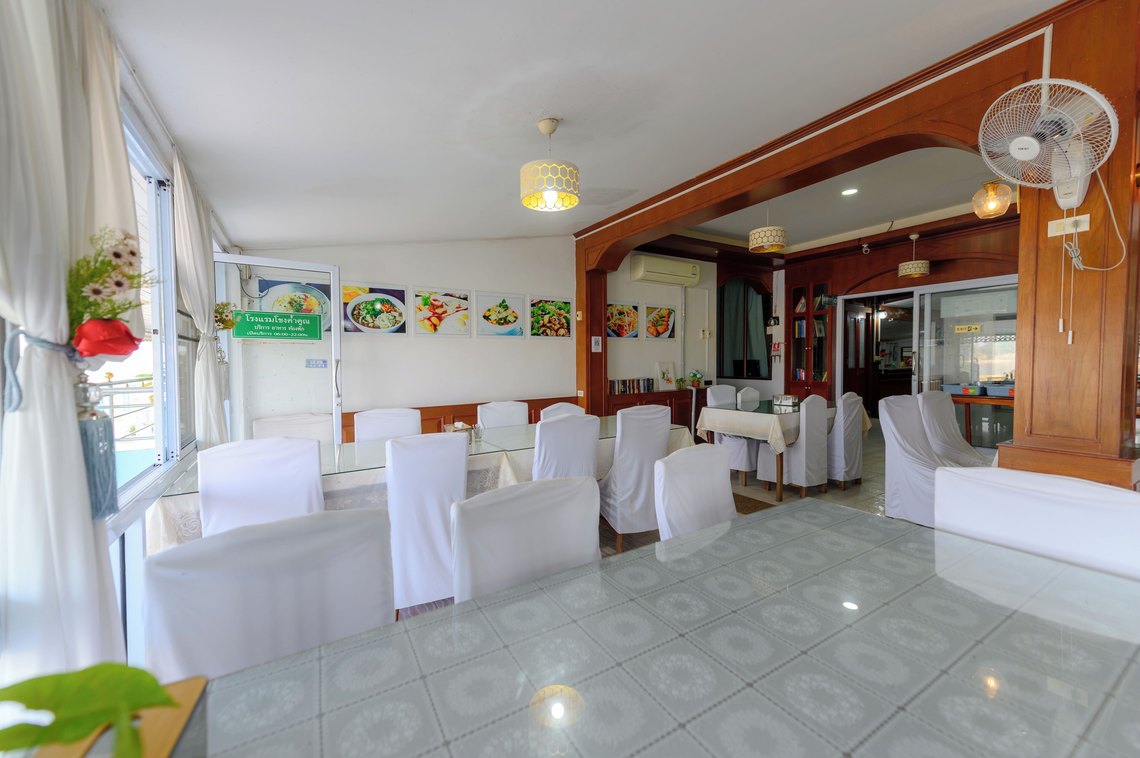 A hotel dining area with white-covered tables and chairs, a tiled floor, and a wooden interior.