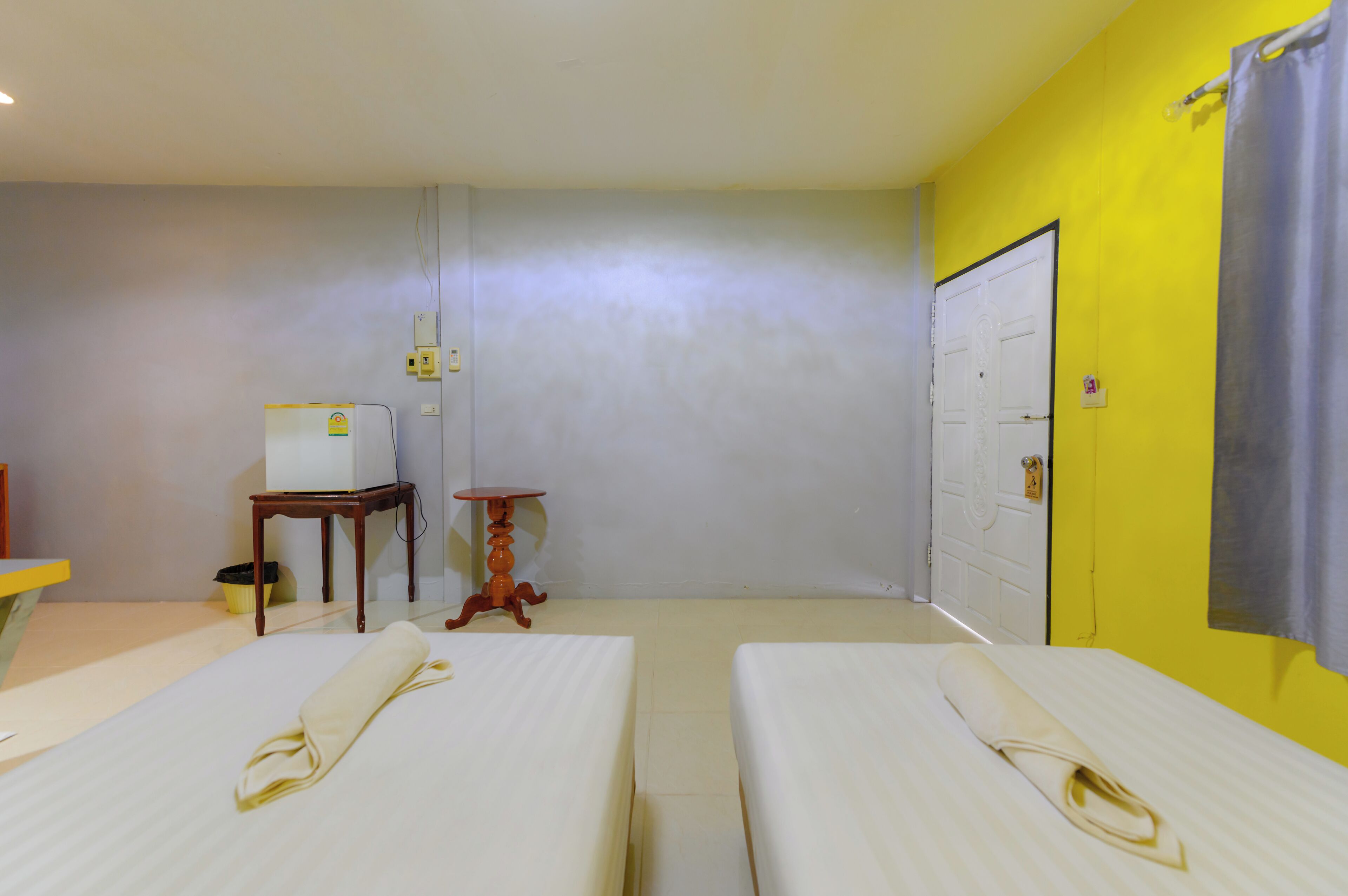 Une chambre d’hôtel avec deux lits, une petite table, un radiateur et une porte.