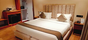 A hotel room with a large bed, wooden furniture, a desk with a coffee maker, and a wardrobe. - ARINA ISLAND RESORT-A BERGAMONT GROUP (Port Blair)