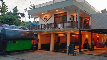 A two-story building with a balcony, a signboard, and a green generator outside.
