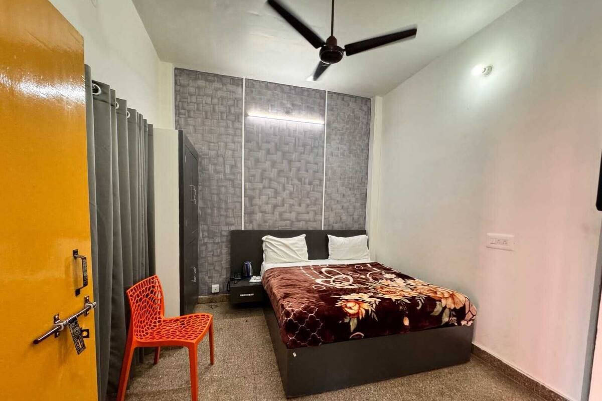 Una camera da letto con un letto, una sedia, un armadio e una ventola a soffitto.