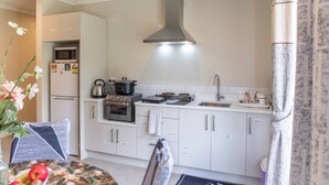 A compact kitchen with a built-in oven, microwave, and a kettle on the countertop. - New two B/room house  attached to house (Pukekohe)