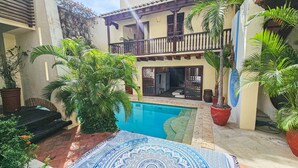 A pool area with a patterned mat, potted plants, and a building with a balcony. - 9 Bedroom Luxury Villa in Old City (Cartagena)
