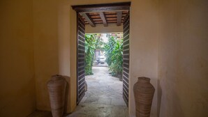 A hallway with a tiled floor leading to a courtyard with plants and a building in the background. - 9 Bedroom Luxury Villa in Old City (Cartagena)