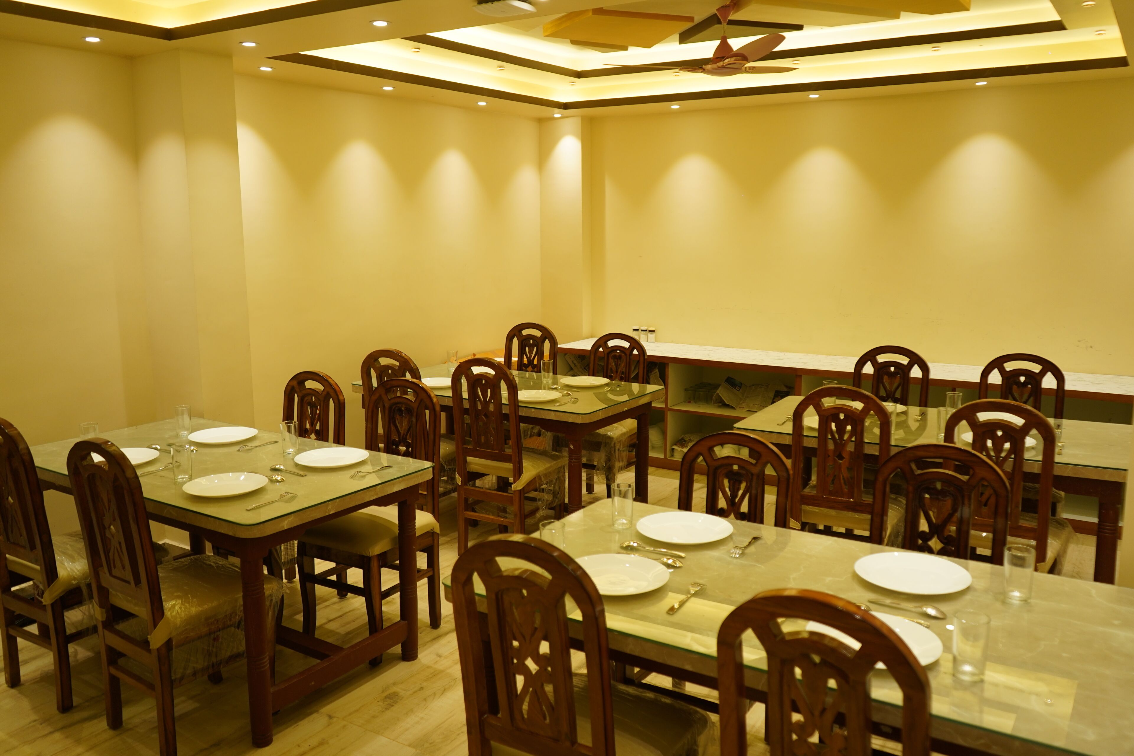 A dining area with multiple tables and chairs, equipped with glass tops and wooden frames.