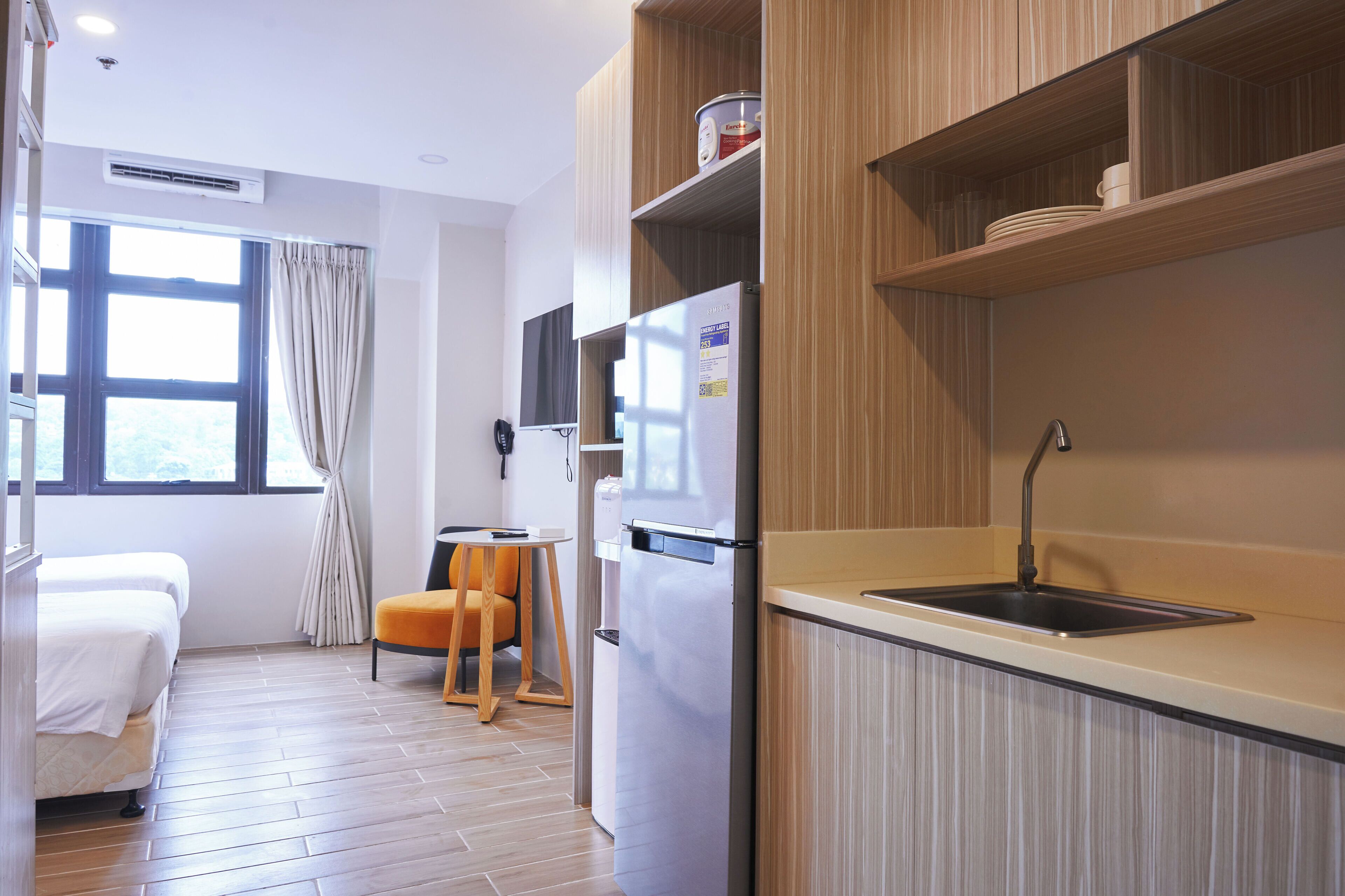 A compact kitchen with a built-in refrigerator, a sink, and wooden shelves.
