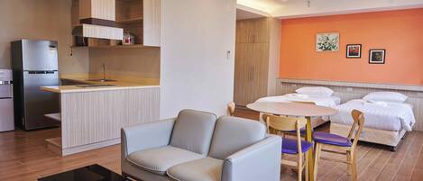 Ein modernes Hotelzimmer mit Küchenzeile, einer Couch, einem Esstisch mit Stühlen und einem Bett.