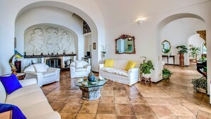 A spacious living room with white sofas, a fireplace, and multiple arches.