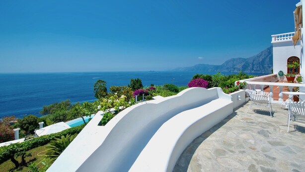 A coastal property with a white exterior, a curved white structure, and a view of the sea.
