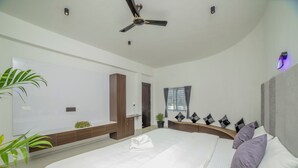 Een moderne slaapkamer met een groot bed, een plafondventilator en een potplant.