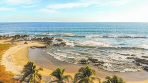 A beach with rocky shoreline, palm trees, and clear blue water. - Casa Irekua Luxury beachfront retreat (Joluta)
