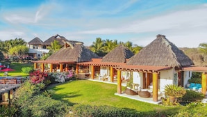 A resort with thatched-roof structures, outdoor seating, and lush landscaping. - Casa Irekua Luxury beachfront retreat (Joluta)