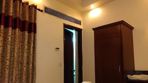 A hotel room with a bed, a wardrobe, a heater, and a curtain. - HOTEL PALM D'OR (New Delhi)