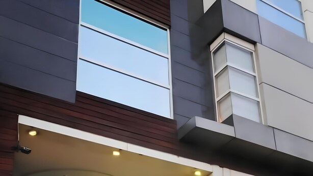 A modern building with large windows and a statue in front. - HOTEL PALM D'OR (New Delhi)