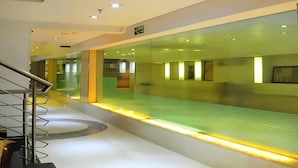A modern interior with a glass partition, a staircase, and a ceiling with recessed lighting. - HOTEL PALM D'OR (New Delhi)