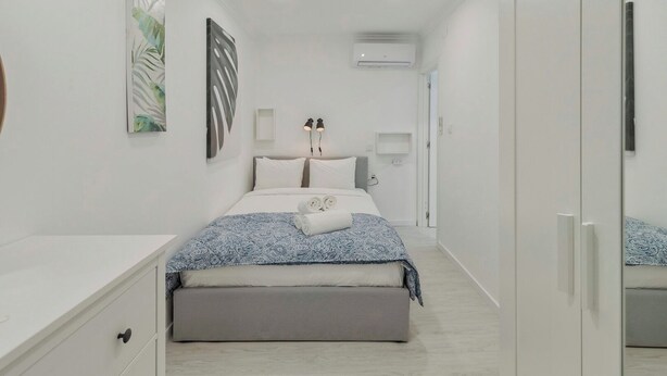 A modern bedroom with a bed, bedside tables, a wardrobe, and a ceiling light.