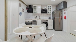 A modern kitchen with white cabinets, a stainless steel refrigerator, a microwave, and a dishwasher.