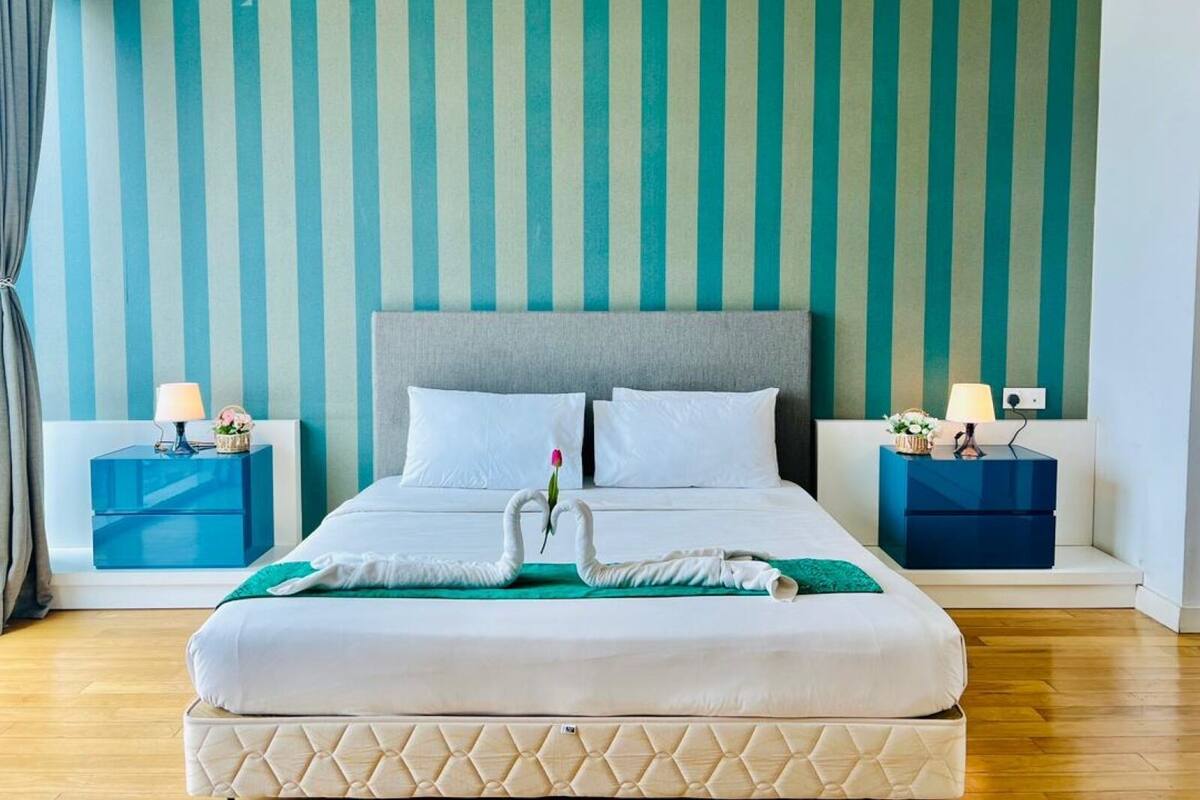 A hotel room with a large bed, two nightstands, and a striped wall.