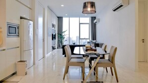 A modern kitchen with white cabinets, a built-in microwave, and a trash bin. - The Platinum Suites KLCC by Moonlight (Kuala Lumpur)