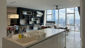 A modern kitchen with a large island, built-in appliances, and a city view through large windows. - The Platinum Suites KLCC by Moonlight (Kuala Lumpur)