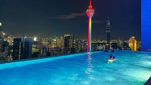 A rooftop pool with a city skyline in the background, including a prominent tower with a rainbow light display. - The Platinum Suites KLCC by Moonlight (Kuala Lumpur)
