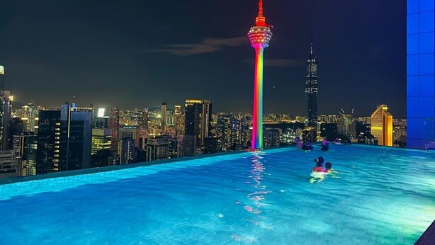A rooftop pool with a city skyline in the background, including a prominent tower with a rainbow light display. - The Platinum Suites KLCC by Moonlight (Kuala Lumpur)