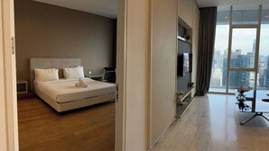A modern hotel room with a large bed, a TV, a dining table, and a city view through large windows. - The Platinum Suites KLCC by Moonlight (Kuala Lumpur)