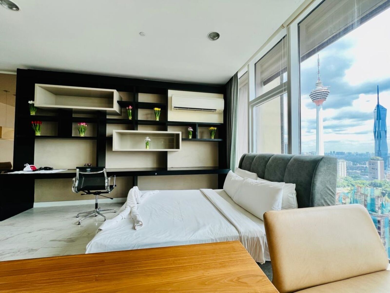 A modern hotel room with a bed, a desk, and a large window with a city view.