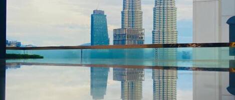 A modern interior with a large reflective pool and a view of the Petronas Towers.