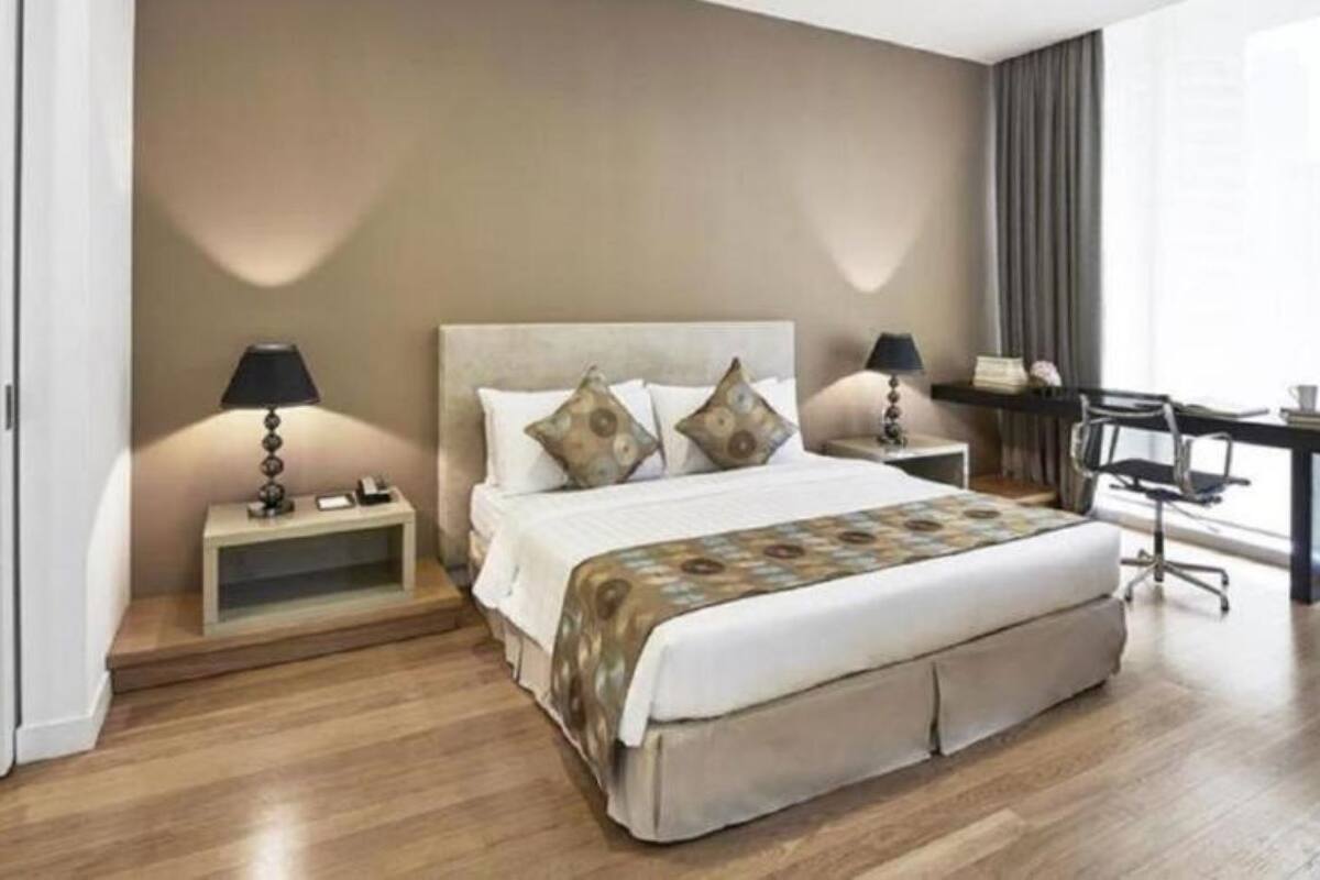 A bedroom with a bed, two bedside tables, a desk, and a chair.