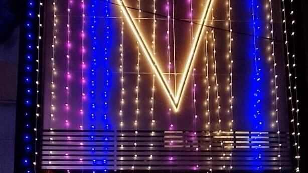 Rakennuksessa on neonvalomainos, jossa lukee ”VAITHI RESIDENCY”, ja sen sisustus on moderni, ja siellä on portaikko sekä oleskelualue.