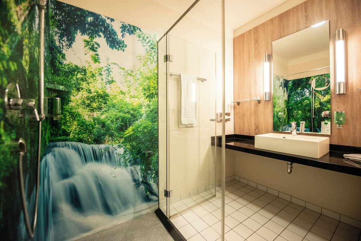 Ein modernes Badezimmer mit Duschkabine aus Glas, Waschbecken und Spiegel.