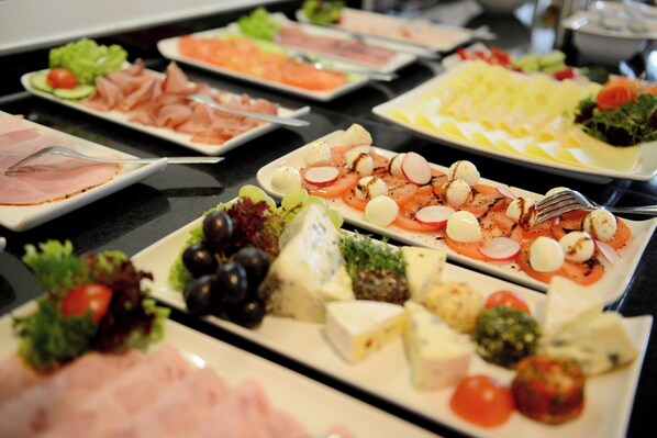A buffet with various food items including meats, cheeses, and vegetables. - Livenwork Hotel&CoWorking GVZ Ingolstadt (Ingolstadt)