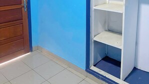 Una habitación con pared azul, una puerta de madera y una estantería blanca con varios compartimentos.